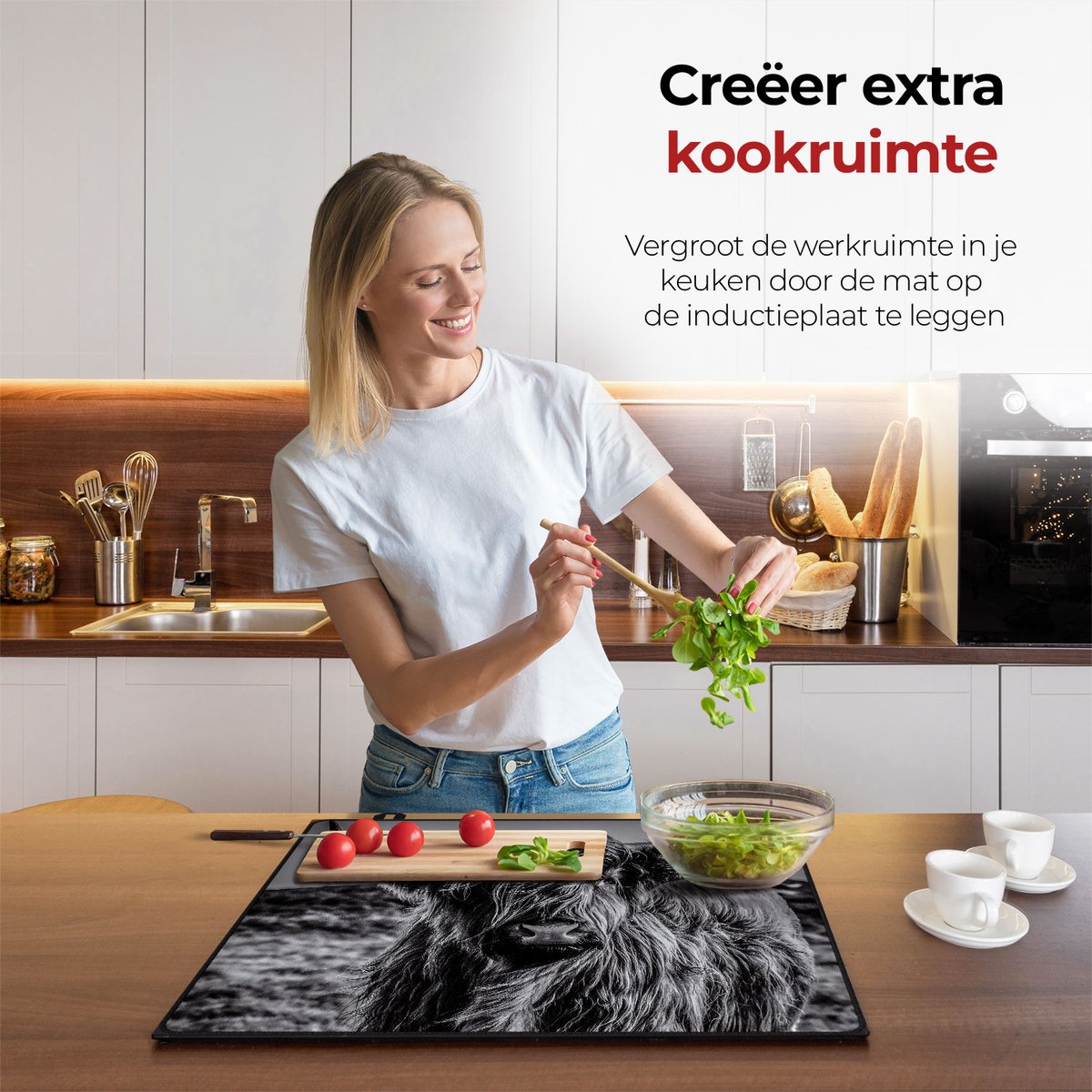 Vrouw in de keuken bezig met eten voorbereiden met behulp van de inductie beschermer Schotse hooglander zwart wit